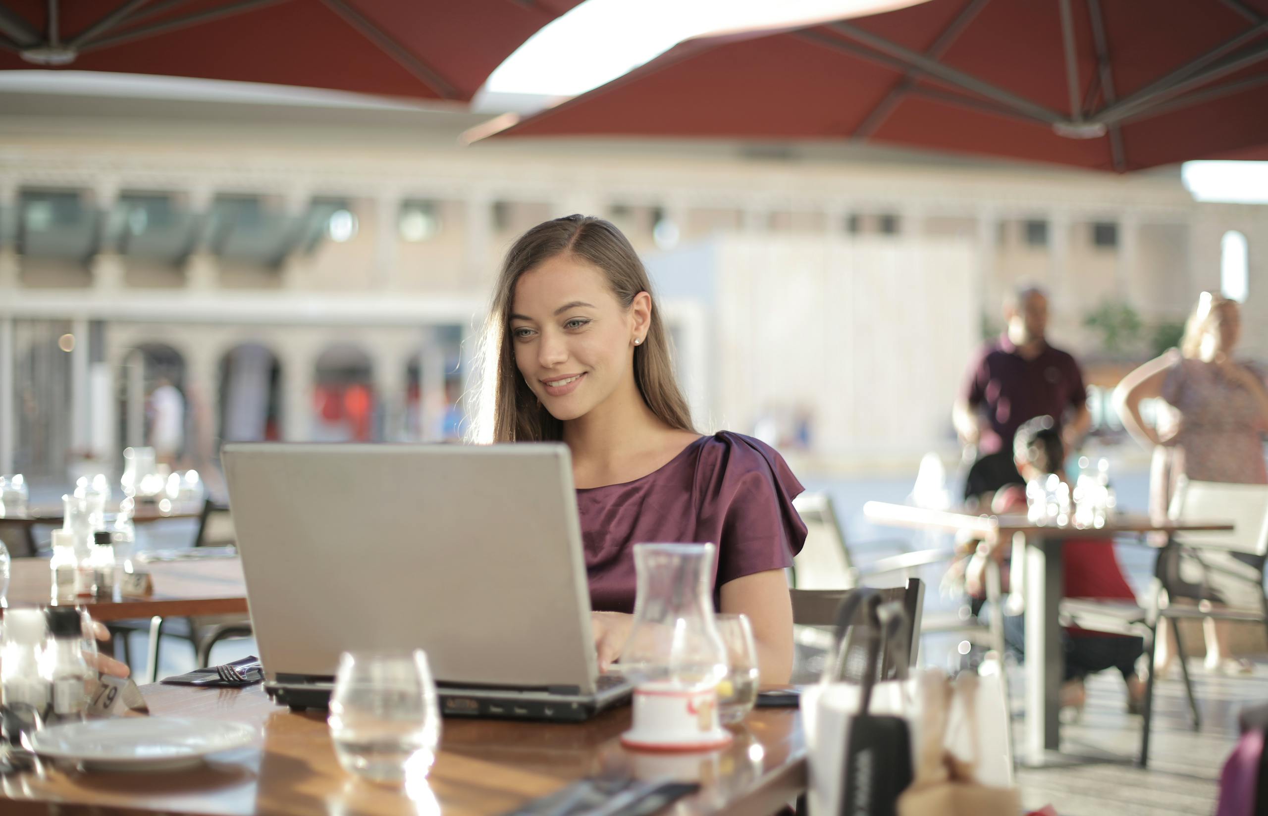 Woman in Purple Shirt Sitting by the Table Using Macbook